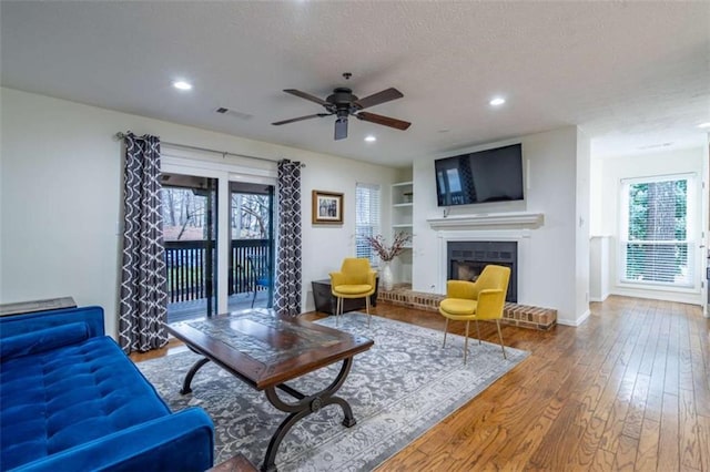 living room featuring visible vents, a brick fireplace, recessed lighting, hardwood / wood-style flooring, and a textured ceiling