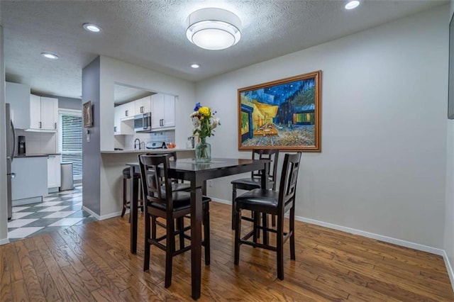 dining room featuring recessed lighting, baseboards, dark wood-style flooring, and a textured ceiling