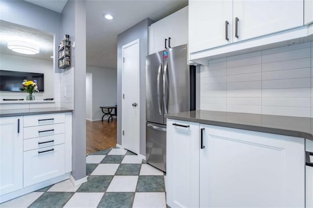 kitchen with dark countertops, tasteful backsplash, white cabinetry, freestanding refrigerator, and dark floors