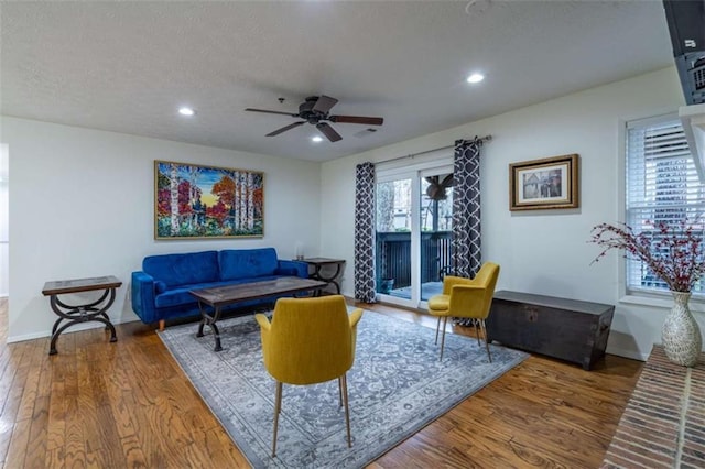 living area with recessed lighting, a fireplace, a textured ceiling, and wood finished floors