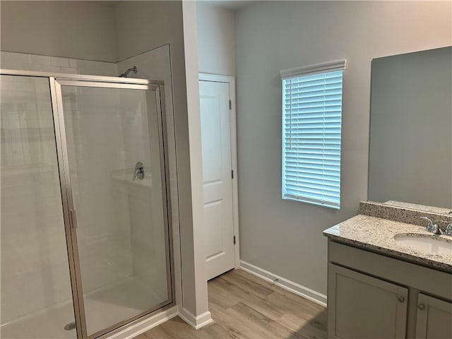 full bath with a stall shower, wood finished floors, vanity, and baseboards