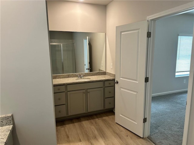 bathroom featuring a shower stall, wood finished floors, and vanity