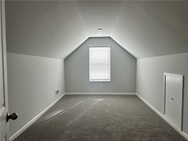 additional living space with carpet, visible vents, vaulted ceiling, and baseboards