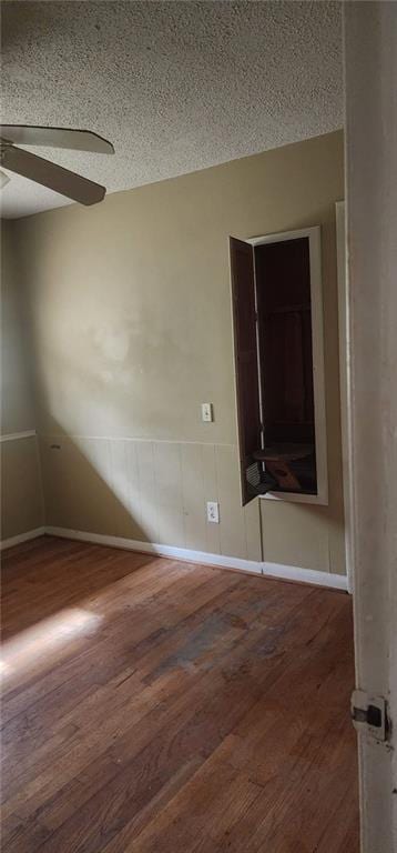 unfurnished room featuring dark wood-type flooring, a textured ceiling, and ceiling fan