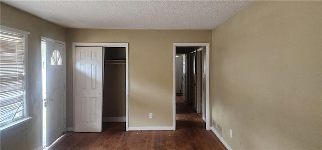 unfurnished bedroom with dark wood-type flooring, a closet, and a textured ceiling