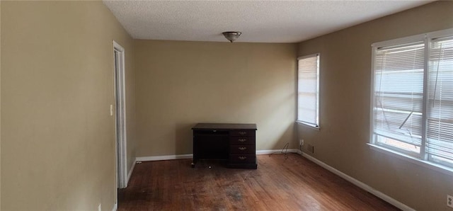 empty room featuring dark wood-type flooring and a textured ceiling