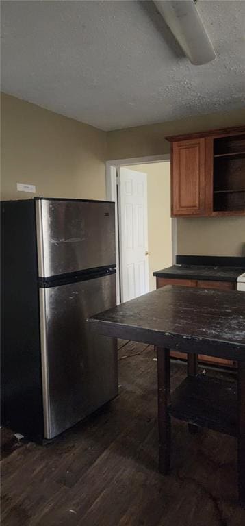 kitchen with dark hardwood / wood-style floors, stainless steel refrigerator, and a textured ceiling