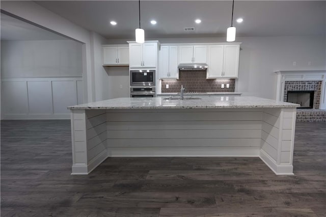 kitchen with stainless steel appliances, white cabinetry, and decorative light fixtures