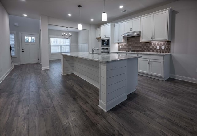 kitchen featuring white cabinetry, decorative light fixtures, oven, and built in microwave