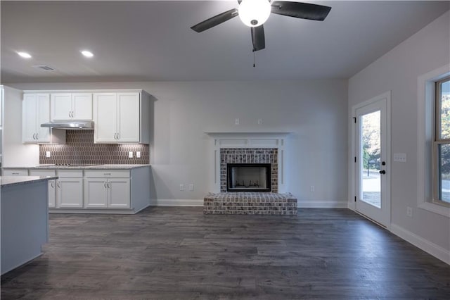 unfurnished living room featuring dark hardwood / wood-style flooring, a fireplace, and ceiling fan