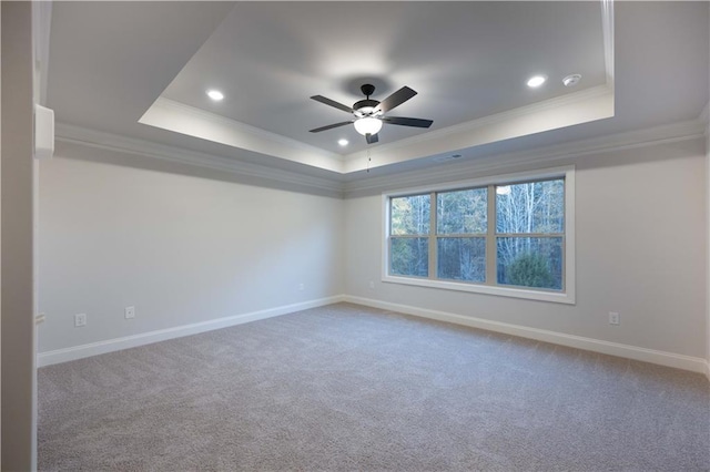 empty room with a raised ceiling, crown molding, carpet flooring, and ceiling fan