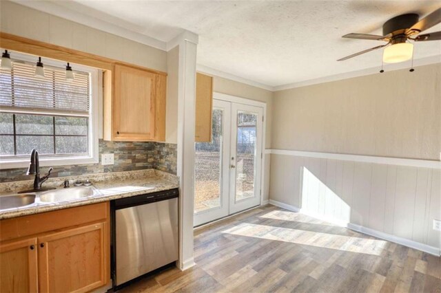 kitchen featuring a sink, light wood finished floors, stainless steel dishwasher, and french doors