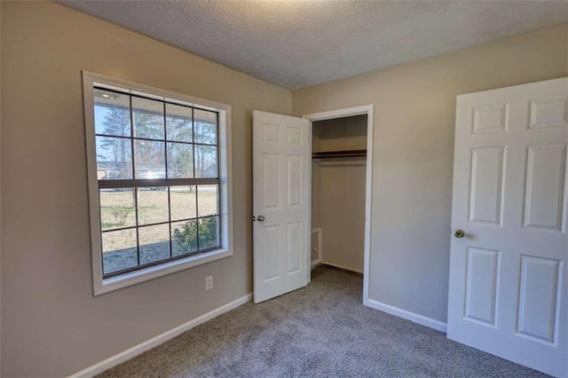 unfurnished bedroom with carpet, a closet, baseboards, and a textured ceiling