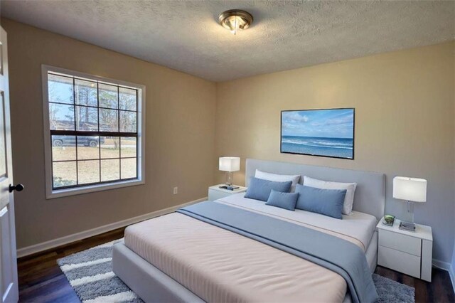 bedroom featuring a textured ceiling, dark wood-type flooring, and baseboards