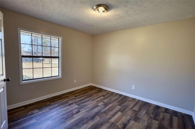 empty room featuring dark wood finished floors, a textured ceiling, and baseboards