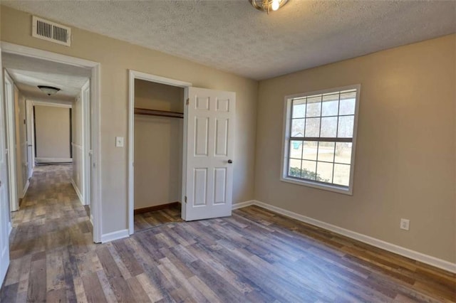 unfurnished bedroom featuring baseboards, visible vents, and wood finished floors