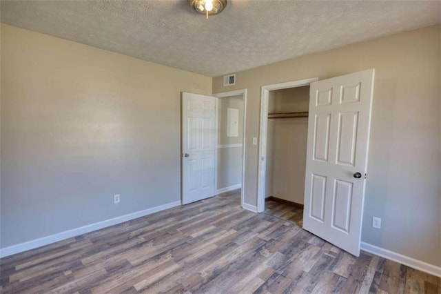 unfurnished bedroom featuring a closet, wood finished floors, visible vents, and baseboards