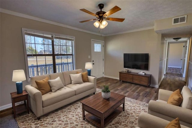 living room with visible vents, crown molding, and wood finished floors