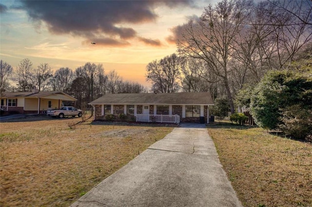 view of front facade featuring covered porch, a yard, and concrete driveway