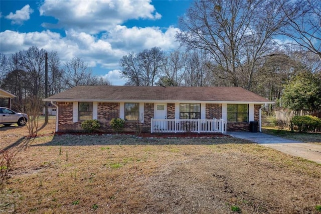 ranch-style house featuring covered porch, brick siding, and a front lawn