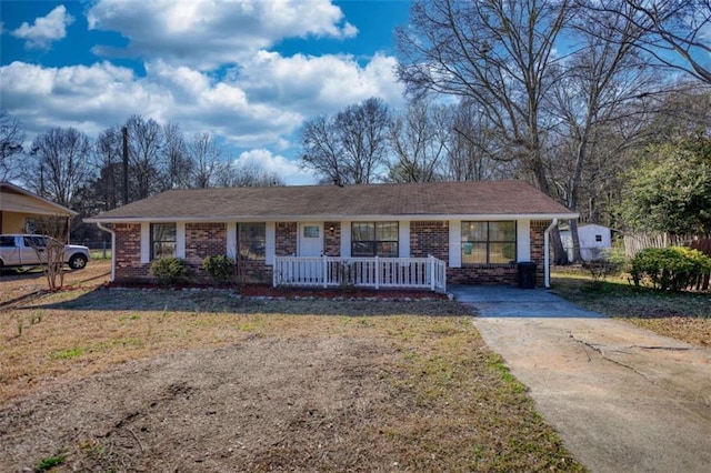 ranch-style home with brick siding, concrete driveway, fence, a porch, and a front yard