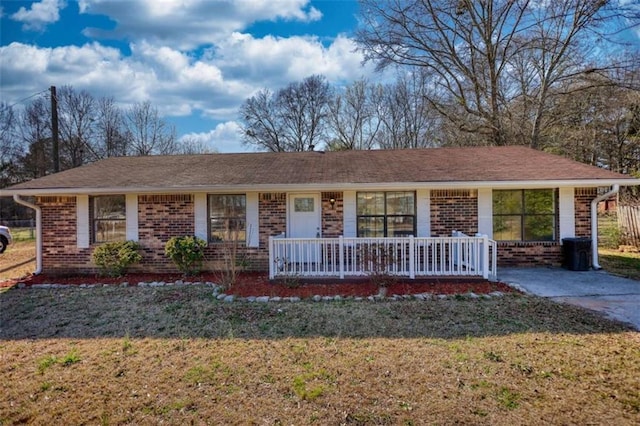 ranch-style house with a front yard, covered porch, and brick siding