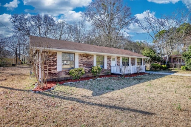 ranch-style home featuring covered porch, brick siding, and a front lawn