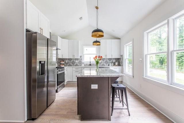 kitchen with backsplash, a kitchen breakfast bar, light hardwood / wood-style floors, and appliances with stainless steel finishes