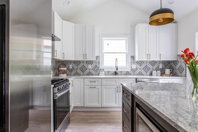 kitchen featuring decorative light fixtures, backsplash, appliances with stainless steel finishes, and white cabinets