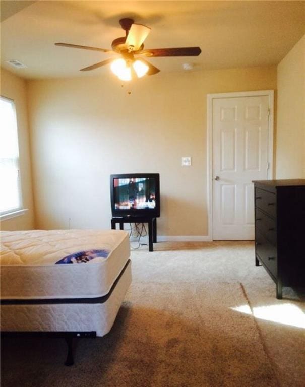 bedroom with a ceiling fan, baseboards, and light colored carpet