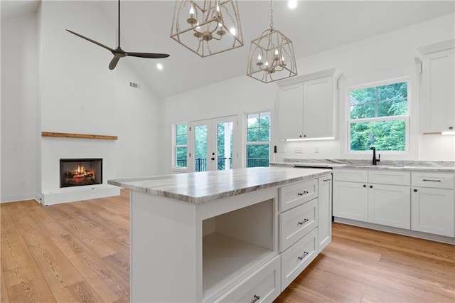 102-A S Cay Dr, Milledgeville, GA 31061 - kitchen with a sink, white cabinetry, high vaulted ceiling, light wood-style floors, and a lit fireplace