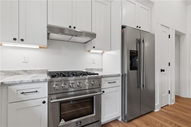102-A S Cay Dr, Milledgeville, GA 31061 - kitchen featuring high quality appliances, under cabinet range hood, light wood-type flooring, and white cabinetry