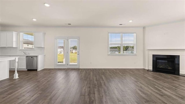 1139 Blue Juniper Cir, Loganville, GA 30052 - unfurnished living room featuring a glass covered fireplace, recessed lighting, baseboards, and dark wood finished floors