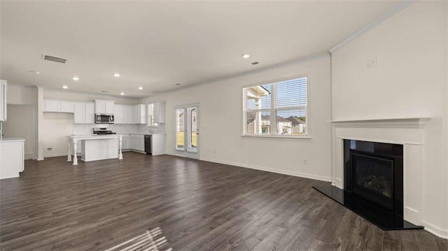 1139 Blue Juniper Cir, Loganville, GA 30052 - unfurnished living room featuring dark wood-style flooring, visible vents, baseboards, and a glass covered fireplace