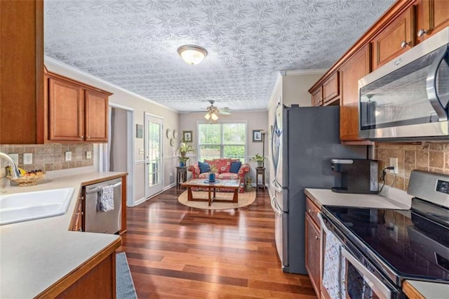 42 Hummingbird Ct, Jefferson, GA 30549 - kitchen with appliances with stainless steel finishes, crown molding, a sink, brown cabinetry, and dark wood-type flooring