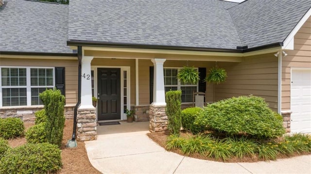 42 Hummingbird Ct, Jefferson, GA 30549 - view of exterior entry with stone siding, covered porch, roof with shingles, and a garage