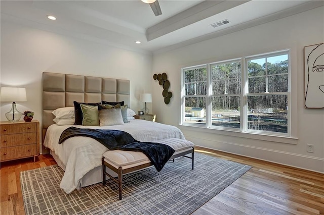 bedroom featuring hardwood / wood-style floors, a tray ceiling, and ceiling fan