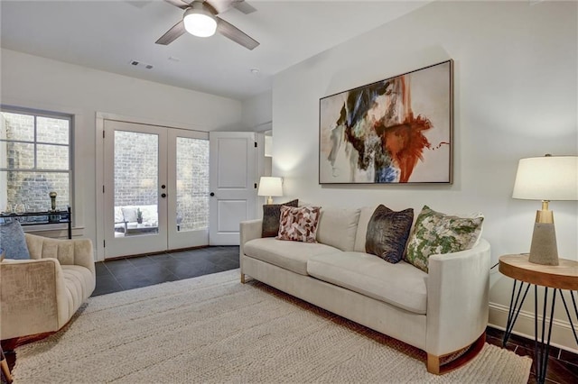 living room with dark tile patterned floors, ceiling fan, and french doors