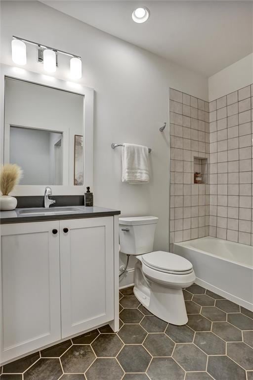 full bathroom featuring tiled shower / bath, tile patterned floors, toilet, and vanity