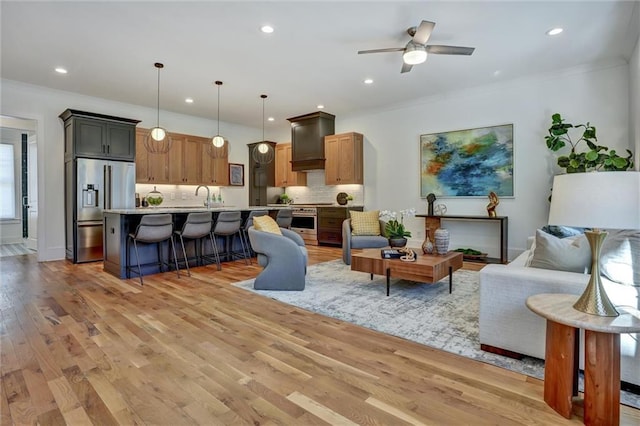 living room with crown molding, sink, ceiling fan, and light hardwood / wood-style flooring