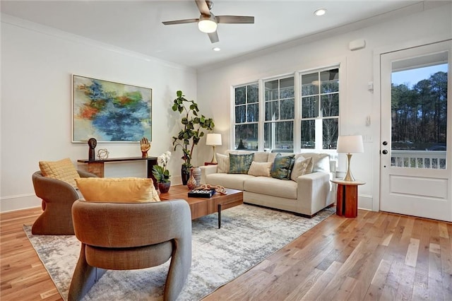 living room featuring hardwood / wood-style flooring, ceiling fan, and crown molding