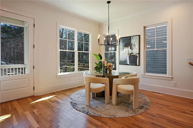 dining space with an inviting chandelier, hardwood / wood-style floors, and crown molding