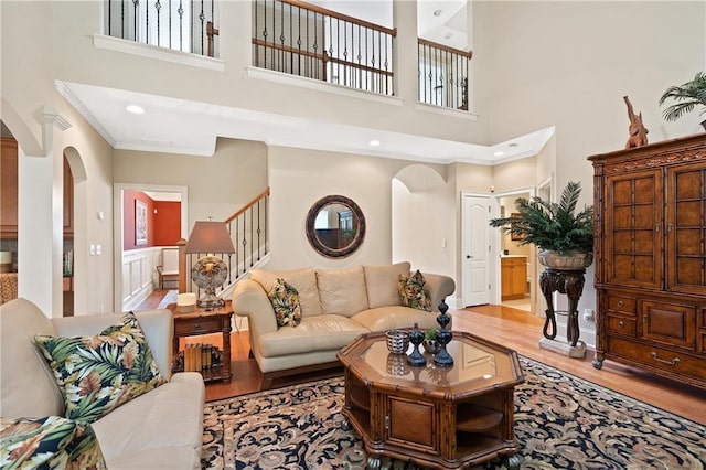 living room featuring arched walkways, stairs, and a towering ceiling
