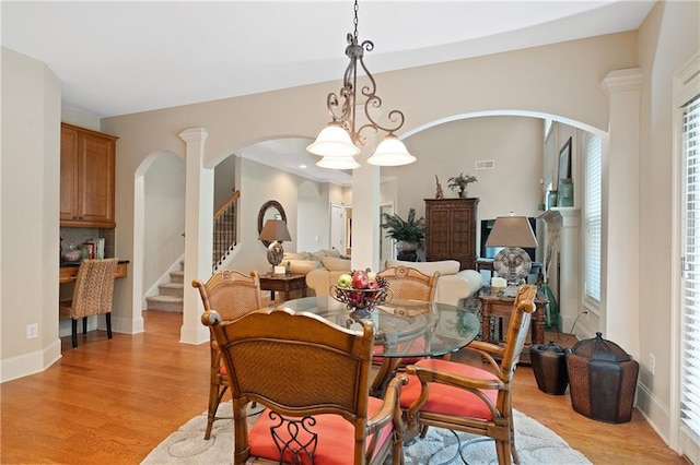 dining room with visible vents, stairway, arched walkways, and light wood-style floors