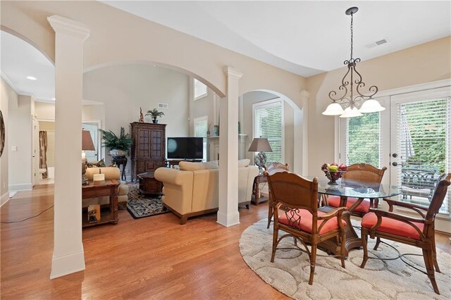 dining room featuring light wood-type flooring, visible vents, arched walkways, and a wealth of natural light