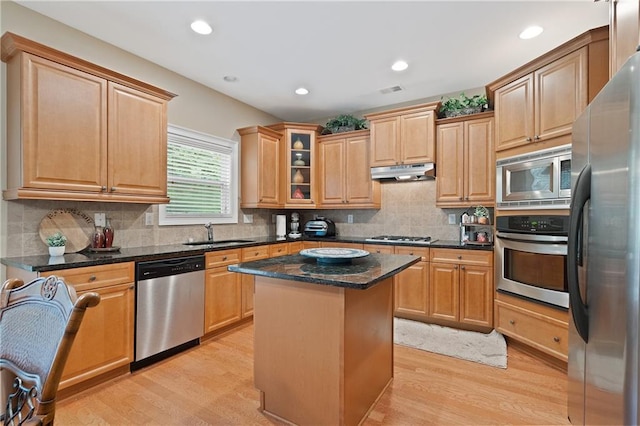 kitchen featuring light wood-style flooring, a sink, appliances with stainless steel finishes, a kitchen island, and under cabinet range hood