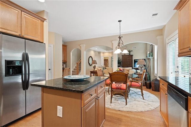 kitchen featuring arched walkways, stainless steel appliances, light wood-style floors, a center island, and visible vents