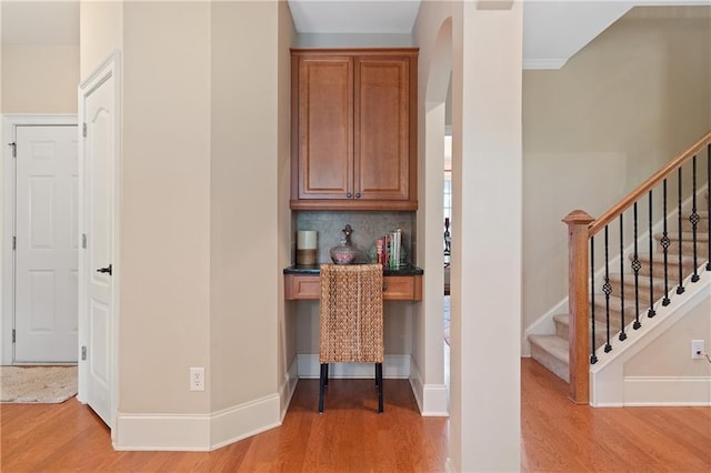 bar with stairway, baseboards, arched walkways, light wood finished floors, and backsplash