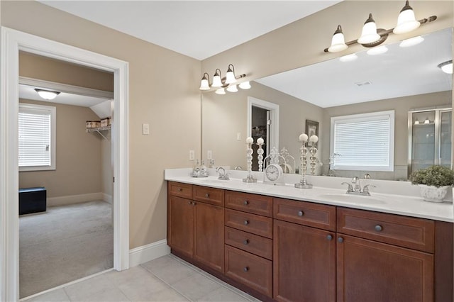 bathroom featuring a shower stall, a sink, double vanity, baseboards, and tile patterned flooring