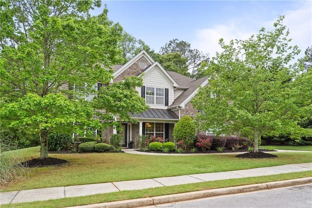 view of front facade with brick siding, a standing seam roof, and a front yard